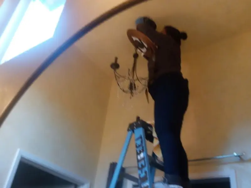 Electrician installing a chandelier in a Polson residence